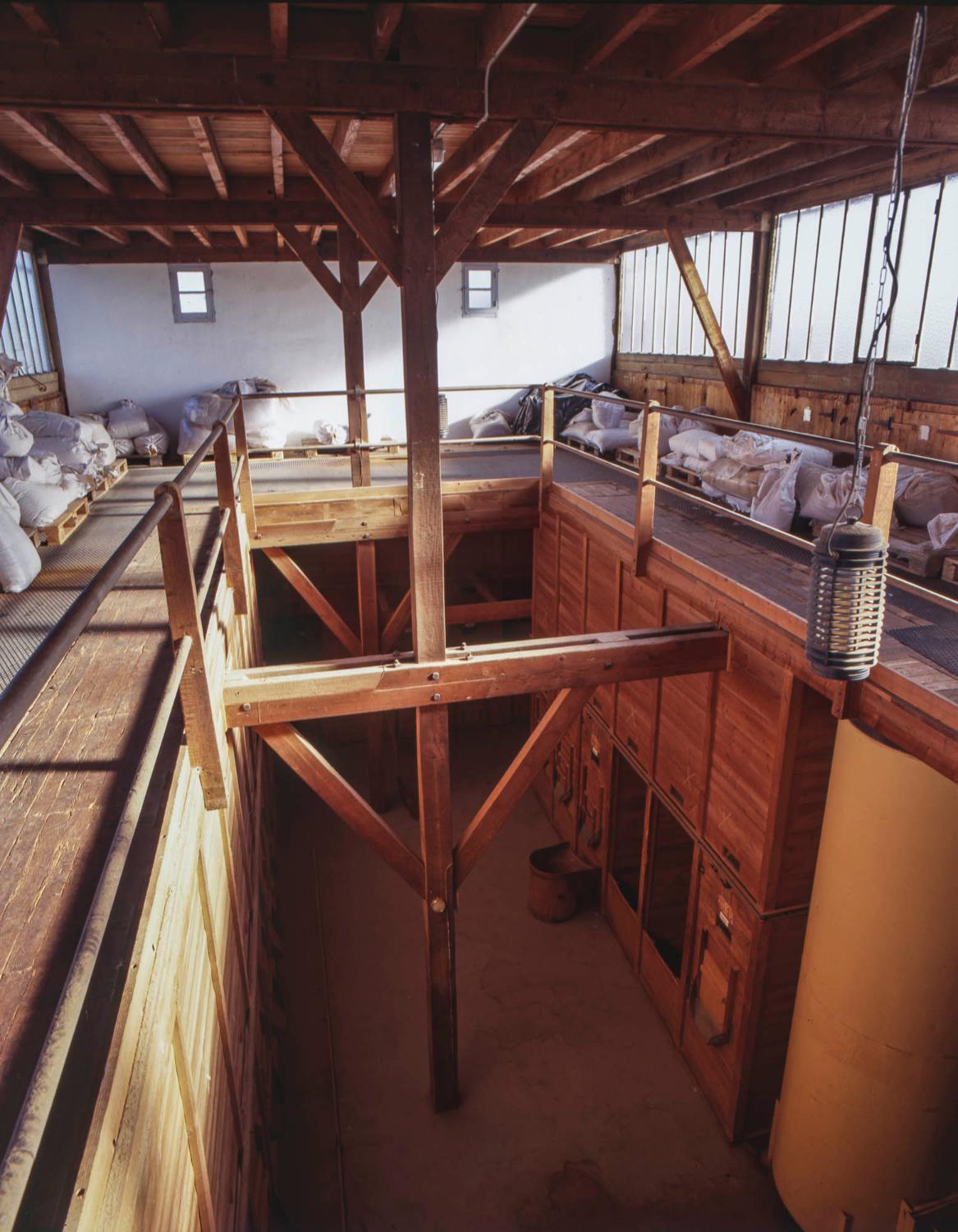 5ème étage ou mezzanine du bâtiment principal. Lieu de stockage (avant les sacs de plantes) de wagonnets contenant les plantes coupées et accès aux trappes permettant de remplir les silos.