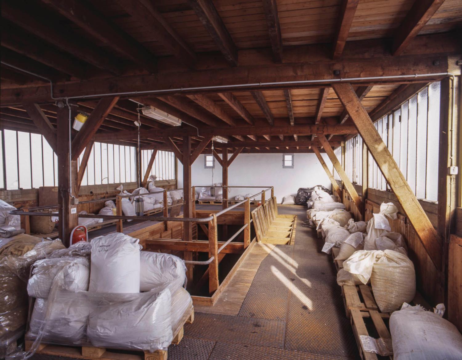 5ème étage ou mezzanine du bâtiment principal. Lieu de stockage (avant les sacs de plantes) de wagonnets contenant les plantes coupées et accès aux trappes permettant de remplir les silos. Détail de trappes ouvertes.