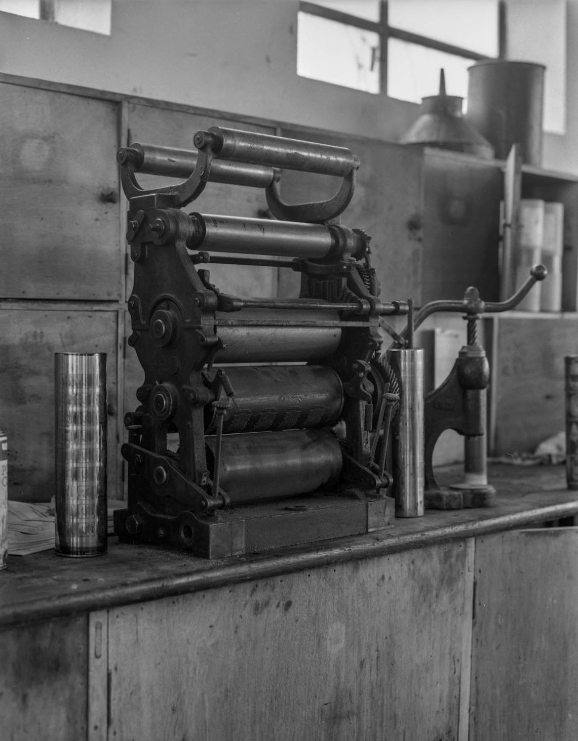 3e étage du bâtiment principal. Atelier d'imprimerie, détail d'un groupe d'impression hélio. A gauche, cylindre permettant l'impression des étiquettes de sachets infusettes. A droite, un appareil pour sertir les capsules de flacons en verre.
