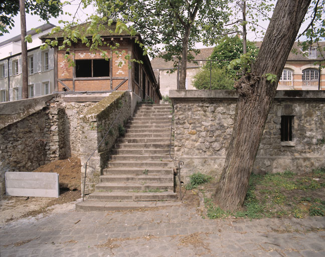 Escalier et mur de soutènement de la cour des communs ; au fond à droite, l'orangerie ; l'escalier descend vers l'ancien potager.