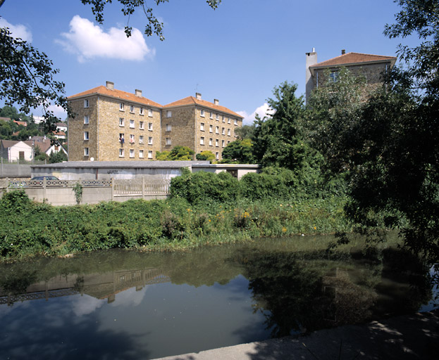 Vue des trois immeubles en meulière construits après la seconde guerre mondiale à l'emplacement de la cité provisoire de l'Orge. Au première plan : l'Orge.