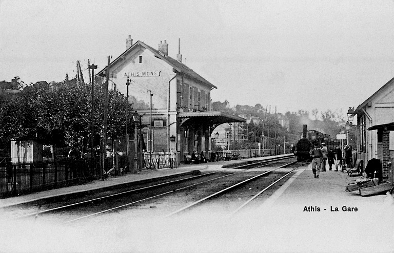 La première gare d'Athis, avant 1902. Sur le quai où arrive le train venant de Paris, abri voyageurs auquel est accolée une maison de garde. La traversée des voies se fait encore à niveau alors qu'un passage souterrain de 3 mètres existe. La marquise métallique a été projetée en 1893.