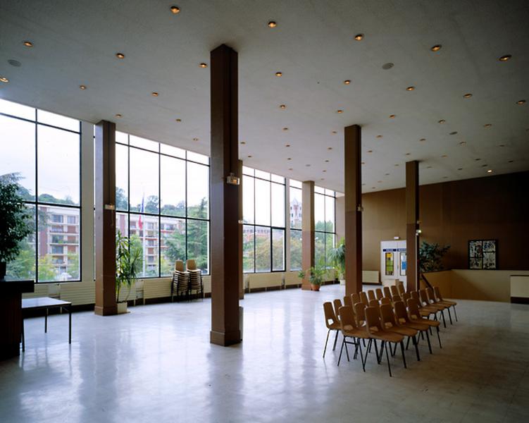 Le foyer de la salle des fêtes : vue perspective en direction de la façade vitrée donnant sur la ville.