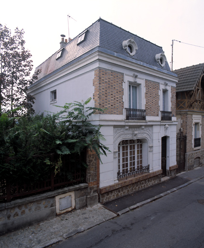 Vue d'ensemble de la maison. La baie principale est surmontée d'un décor de stuc Des afrafes moulurées ornent le linteau des quatre baies.