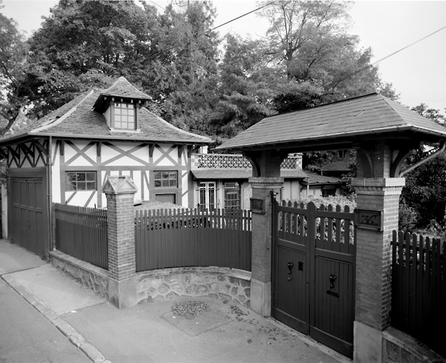 Vue du portail d'entrée et bâtiment des communs en bordure de la rue.
