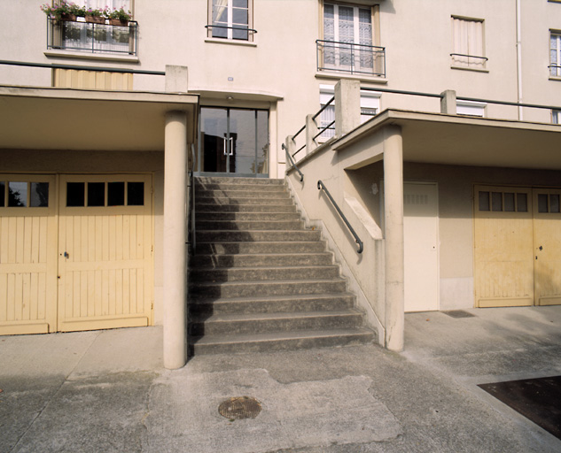 Escalier situé dans l'axe de la porte d'entrée de l'immeuble, entre les garages formant terrasse.