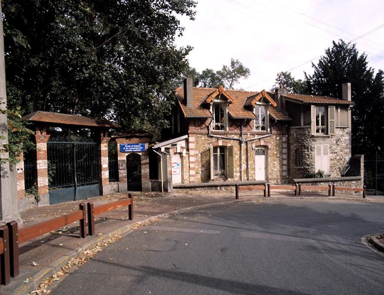 Vue de la grille d'entrée et de la maison de gardien.