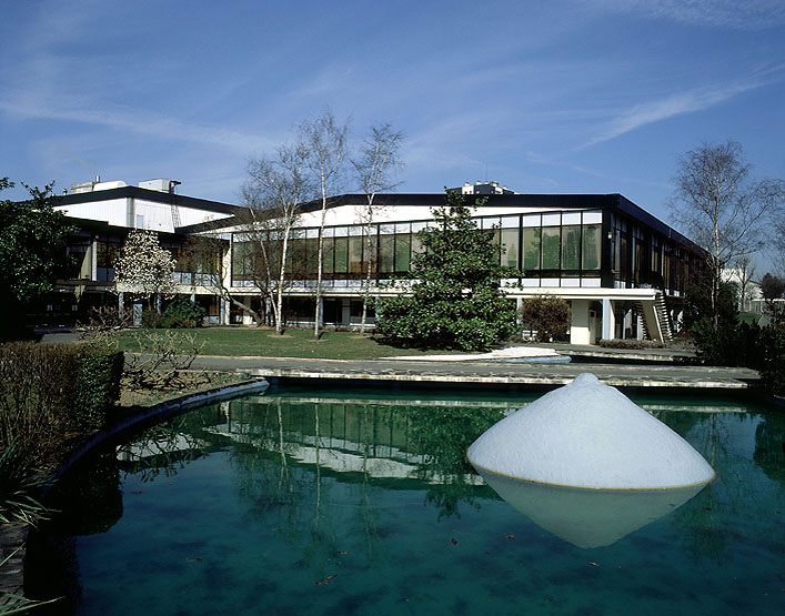 Vue d'ensemble des premiers bâtiments de l'usine ainsi que des aménagements paysagers. Au premier plan, sur le plan d'eau, est placé le Sein, oeuvre du sculpteur César.
