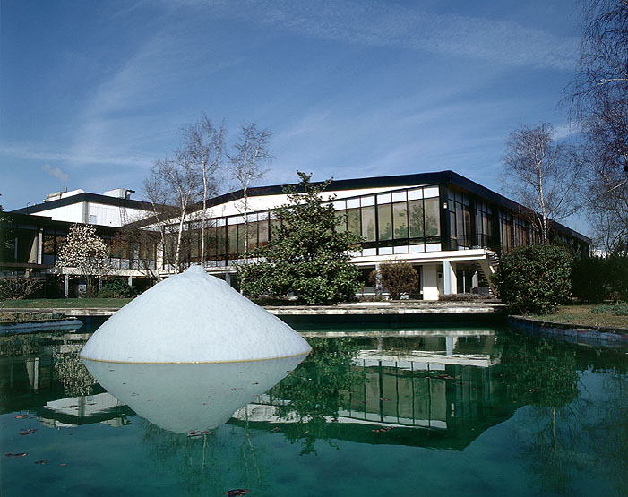 Vue d'ensemble des premiers bâtiments de l'usine ainsi que des aménagements paysagers. Au premier plan, sur le plan d'eau, est placé le Sein, oeuvre du sculpteur César.