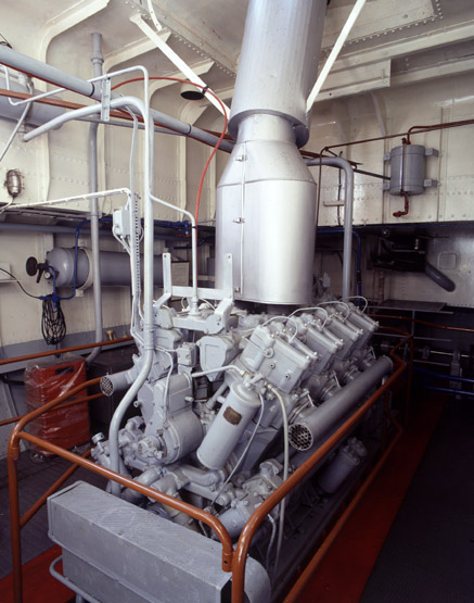 La salle des machines. Le moteur est à huit cylindres surmontés d'un silencieux d'échappement. A gauche, une bouteille à air comprimé pour le lancer.