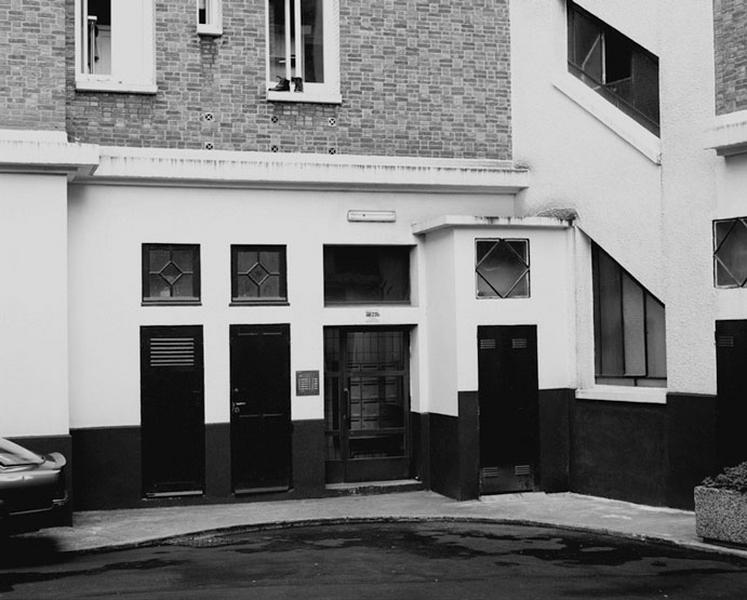 Vue de l'entrée et de la cage d'escalier d'un immeuble sur cour.