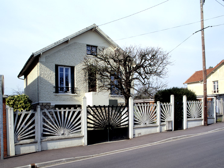 Vue de la façade principale. Les dessins de la clôture, du portail et de la ferronnerie se répondent.