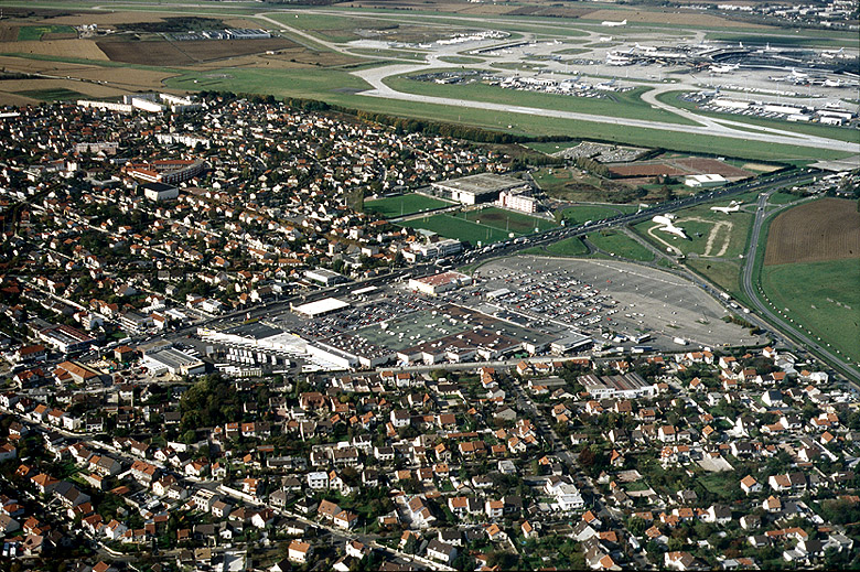 Vue aérienne de la zone pavillonnaire de part et d'autre de la RN 7 ; à gauche Paray-Vieille-Poste avec l'école Jules-Ferry et l'enclave du centre sportif Paul-Demange situé sur le territoire d'Athis-Mons ; au fond, les pistes de l'aéroport d'Orly. Cliché DDE, octobre 1994.