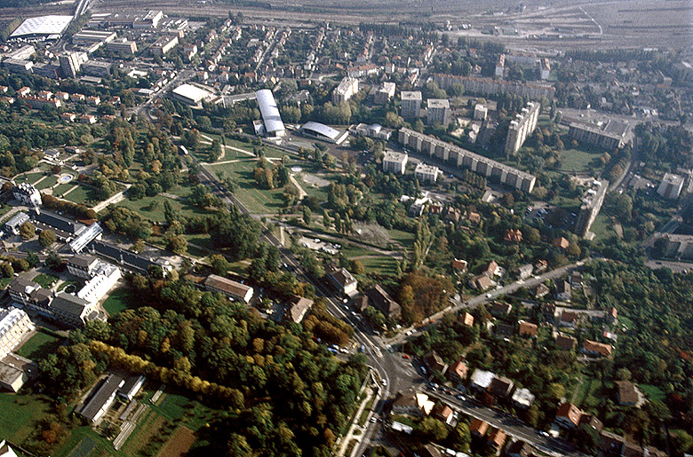 Vue aérienne : château d'Ozonville, mairie, avenue Aristide-Briand et quartier d'Athis-Val à l'arrière-plan ; au fond, immeuble HLM construit par la SNCF et Cité des Fleurs.