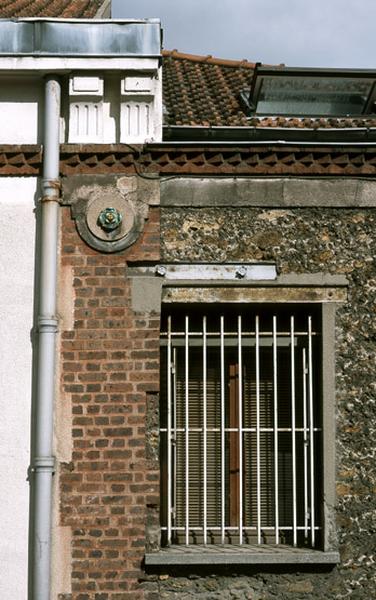 La façade sur la rue Romain-Rolland associe brique et meulière rocaillée. Le chaînage est surmonté d'un fleuron en céramique et de deux consoles trigliphées.