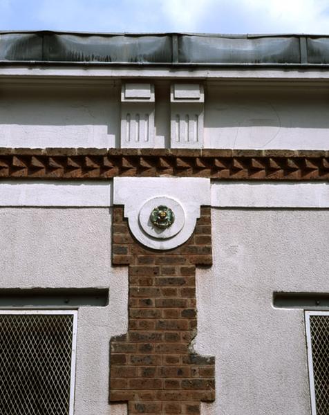 Détail de la façade sur la rue Romain-Rolland : corniche et chaînage de brique.