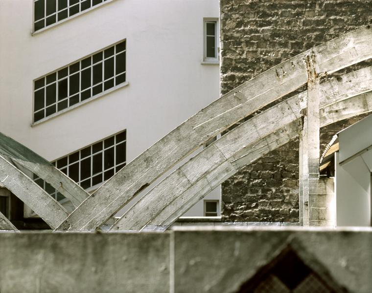 Détail d'un arceau en béton armé et du système de fixation, également en béton armé, de la toiture suspendue.