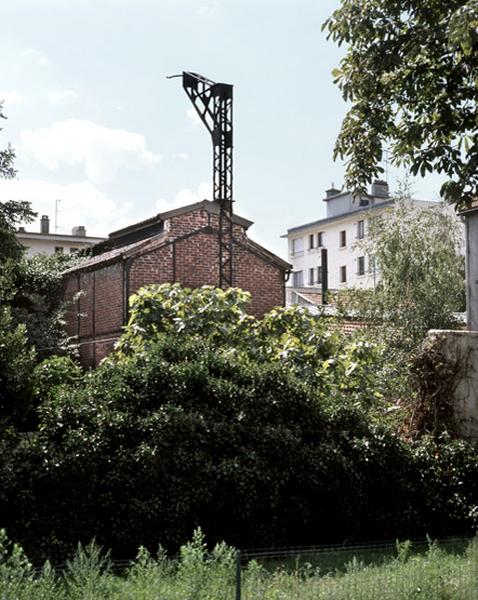 Vue, depuis le nord, du pignon de la halle de fonderie abritant les cubilots avant leur démantellement vers 1970. La potence maintenait la cheminée des fours.