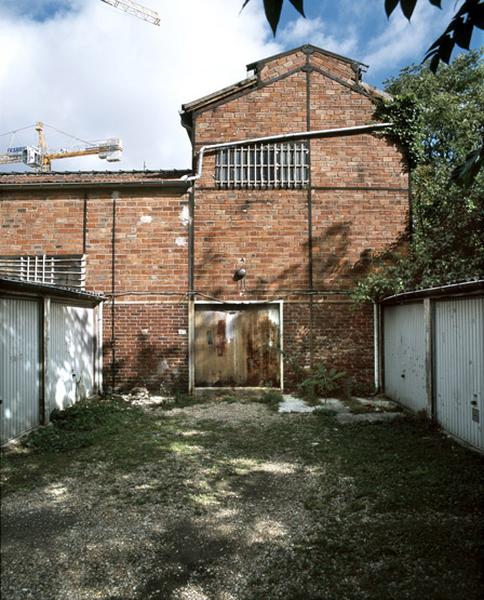 Pignon sud de la halle abritant itinialement l'étuve, dans le prolongement de la halle de fonderie abritant les cubilots. Un appentis, aujourd'hui démoli, était adossé au pignon pour abriter diverses matières premières.