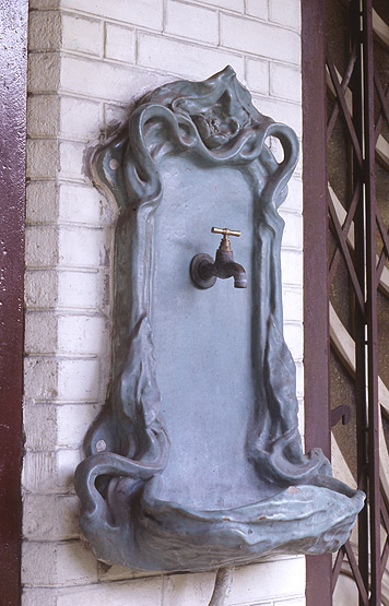 Détail de la fontaine en fonte ornant la façade.