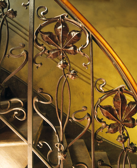 Détail de la ferronnerie de la rampe d'escalier aux motifs de feuilles de chataignier.