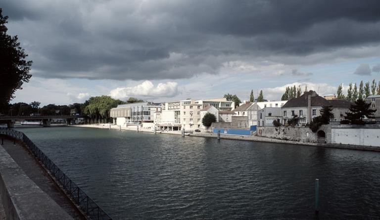 La partie occidentale de l'île Saint-Etienne, vue depuis la rive sud (quai Hipployte-Rossignol). De gauche à droite : la médiathèque, l'université (ancienne trésorerie), l'emplacement des Moulins, la poterne des Nonettes.