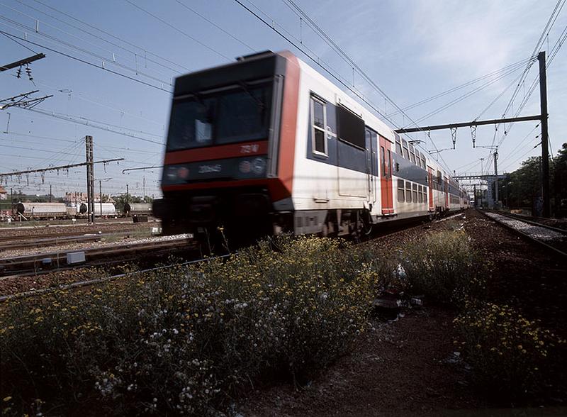 La gare et ses voies ferrées : rame de banlieue à deux étages entrant en gare sur le réseau P.L.M.