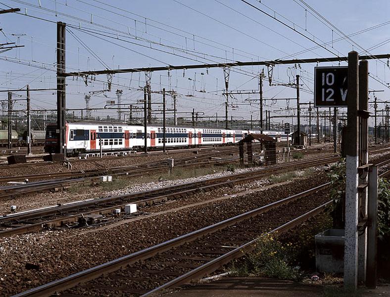 La gare et ses voies ferrées : rame de desserte de banlieue à deux étages entrant en gare de Juvisy sur le réseau P.L.M.