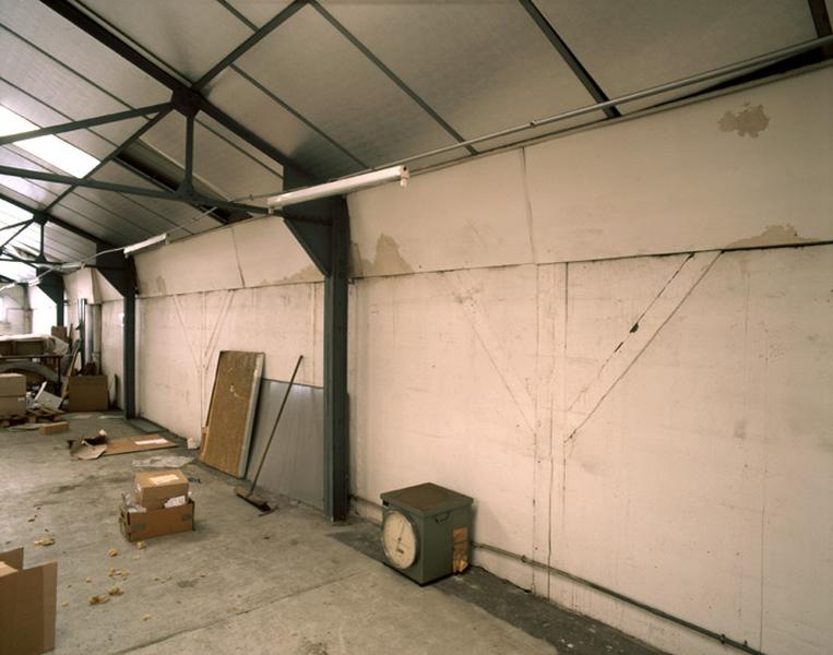 Intérieur du bâtiment de 'stockage du matériel'. Les murs à pans de bois hourdés de brique ont été coiffés tardivements d'une charpente métallique.