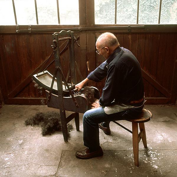 M. *, qui a fait son apprentissage dans l'atelier de tapisserie, restitue quelques gestes du travail. La cardeuse à main ou balancelle permet d'ouvrir le crin, destiné par exemple à uniformiser le fond d'un fauteuil.