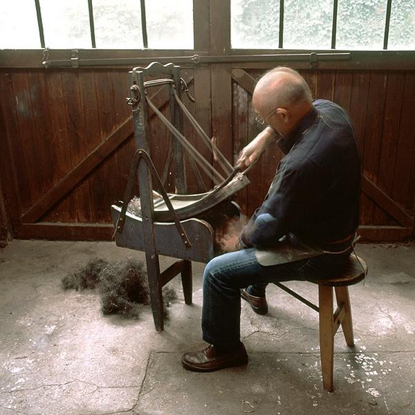 M. *, qui a fait son apprentissage dans l'atelier de tapisserie, restitue quelques gestes du travail. La cardeuse à main ou balancelle permet d'ouvrir le crin, destiné par exemple à uniformiser le fond d'un fauteuil.