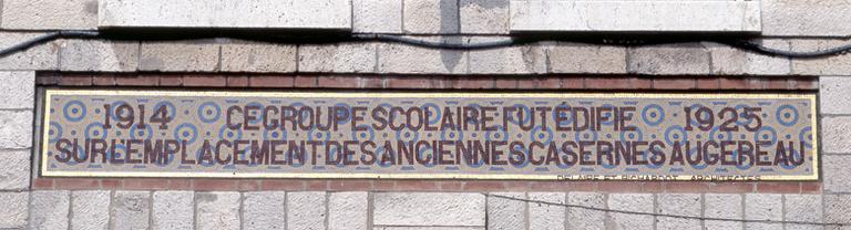 Détail de l'inscription en mosaïque sur le pignon est : '1914-1925. Ce groupe scolaire fut édifié sur l'emplacement des anciennes casernes Augereau. Delaire et Richardot architectes'.