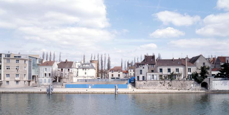 Le quai de la Reine-Blanche, sur l'île Saint-Etienne, vu depuis la rive sud en 2006 : la dent creuse au centre correspond au site des Moulins de Melun.