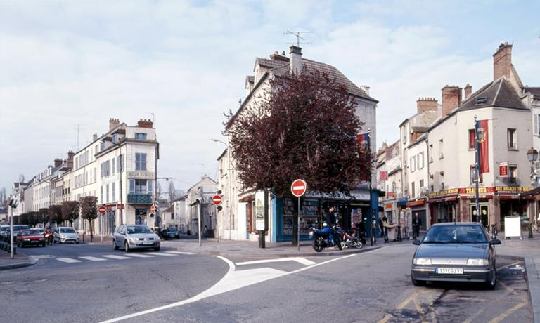 Vue de la partie occidentale de la place Saint-Jean : de gauche à droite s'ouvrent le boulevard Gambetta (sur l'emprise des anciennes fortifications d'agglomération mises en place sous Philippe Auguste), la rue Eugène-Briais (ancienne rue Neuve), la rue René-Pouteau (ancienne rue de la Juiverie) et l'amorce de la rue Paul-Doumer (ancienne rue aux-Oignons puis rue de l'hôtel de ville).