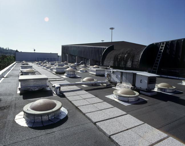 La piscine couverte : vue d'ensemble des toitures. A gauche, le toit des vestiaires. A droite, celui des bassins, plus élevé.