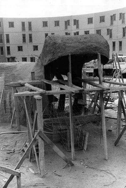 Vue du chantier prise le 17 avril 1973, de la place du Bestiaire. Au premier plan, l'hippopotame vu de face dont seule la partie supérieure de la gueule est façonnée, encore supportée par une armature de bastings. Le ferraillage de la partie inférieure de la gueule est en place.