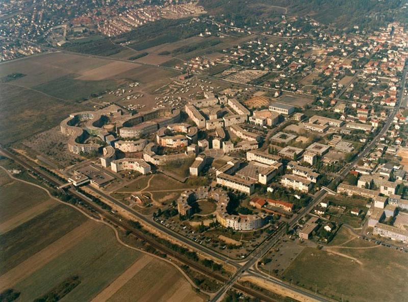 Vue aérienne de la partie ouest du quartier jusqu'à la route de Poissy. Une grande partie des bâtiments a déjà été réhabilitée (à l'exception de la place de l'Hippodrome, de celle du Bestiaire et de l'Ellipse). L'isolation par l'extérieur a caché les compositions colorées voulues par Aillaud. On aperçoit des frontons triangulaires couronnant certaines travées de bâtiments. La passerelle piétonne permettant de franchir la route de Poissy est encore en place.