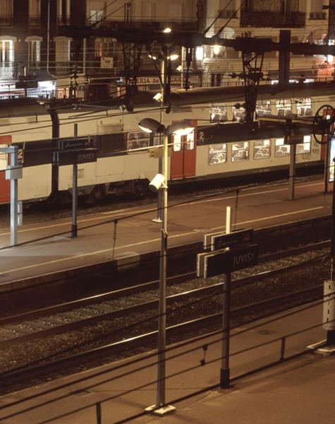 La gare et ses voies ferrées : la gare voyageurs au passage d'une rame de banlieue.