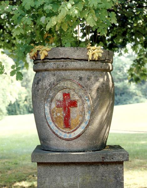 Jardinière en ciment dans le parc de l'hôpital portant la croix de saint Camille.
