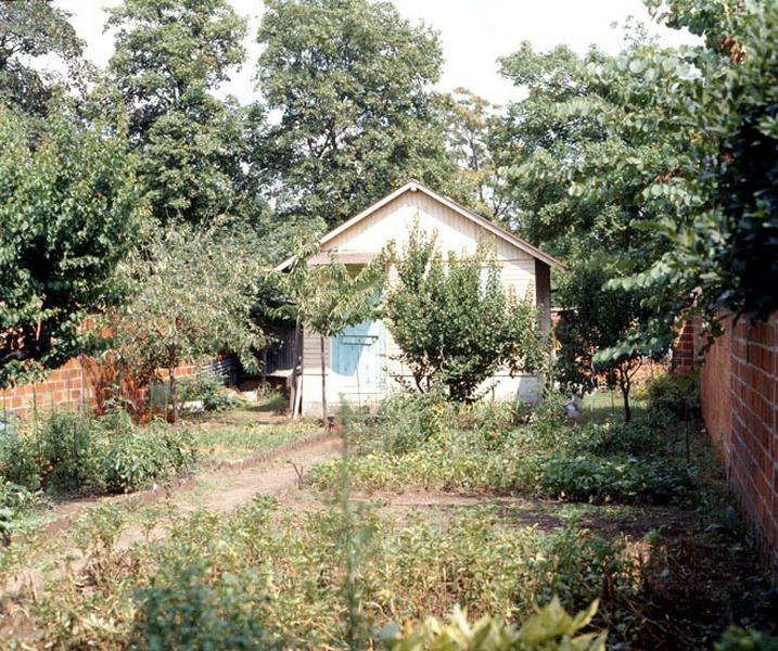 Vue d'ensemble d'un cabanon construit au fond d'un jardin potager.