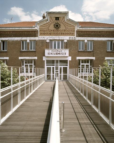 Vue depuis la passerelle enjambant l'avenue et reliant le bâtiment d'origine à l'extension récente (la cantine), vers le fronton présentant la citation d'Emile Zola : 'La France vaudra demain ce que vaudra l'école'.