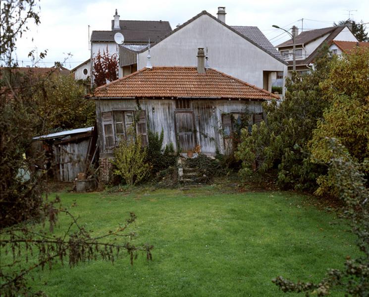 Vue de la petite barraque en bois implantée au bord d'un vaste terrain verger.