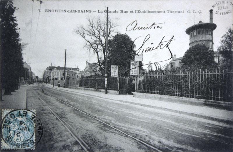 Vue des grilles de clôture du jardin de l'établissement thermal depuis la 'Grande rue', actuel boulevard du Général de Gaulle.
