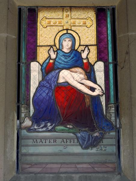 Vue de la verrière signée du maitre verrier Charles Champigneulle, au fond de la chapelle : mère de douleur.