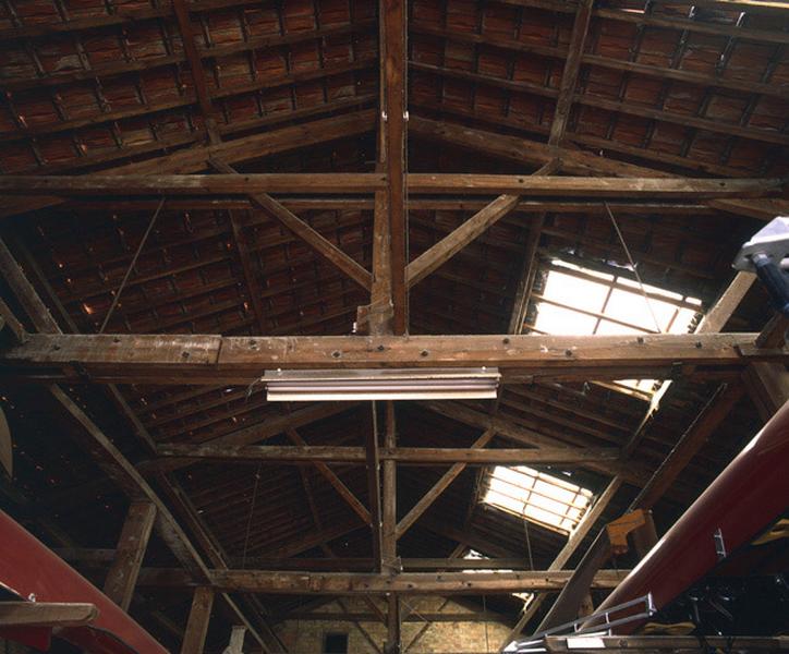 Vue intérieure de la charpente du 2e hangar à bateaux, montrant la structure à entrait et faux-entrait.