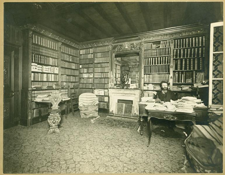 Camille Flammarion assis à son bureau dans sa bibliothèque.