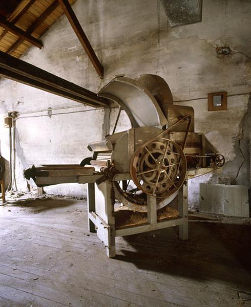 Vue du mécanisme de fonctionnement d'une cardeuse à un seul tambour cardant située à l'étage de combles de l'entrepôt industriel.
