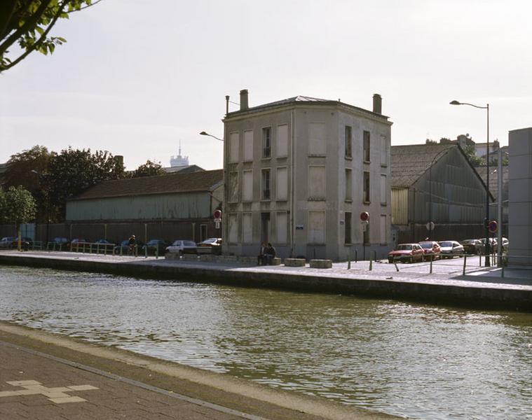Vue de l'immeuble d'habitation, logement des employés des Comptoirs Français E. Mignot, situé à l'angle de la rue Etienne Marcel et du quai de l'Aisne depuis la rive droite du Canal de l'Ourcq.