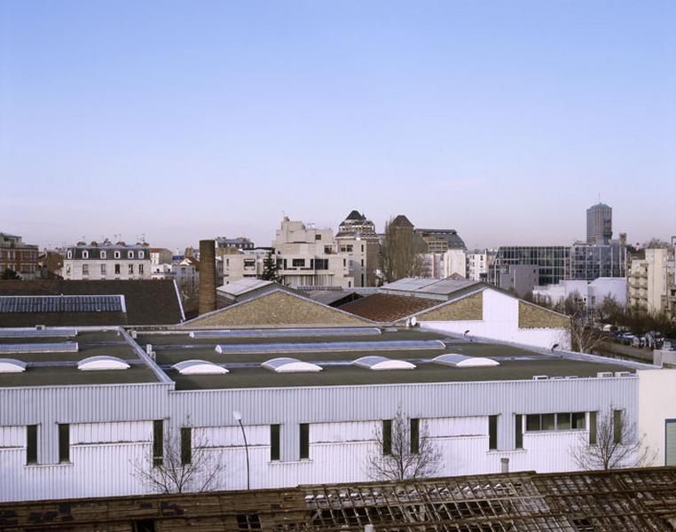 Vue des toits des entrepôts et de la cheminée d'usine du site Boch Frères depuis la terrasse de l'atelier de fabrication de la manufacture de meubles F. Louis.