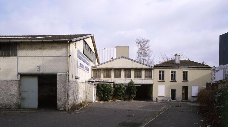 Vue des entrepôts, ancien atelier de réparation des véhicules automobiles des Comptoirs Français E. Mignot, et du logement du gardien (à droite) depuis la cour.